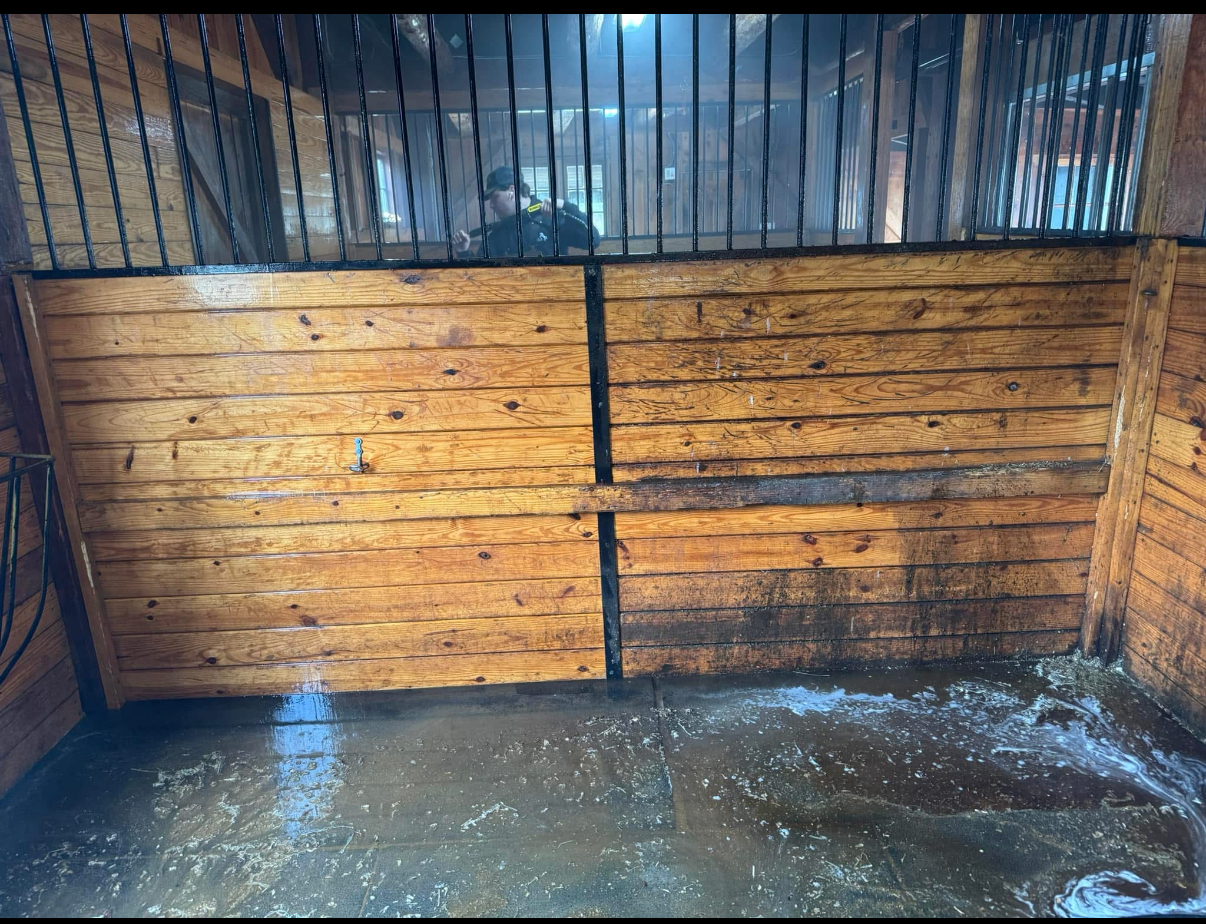 Crew mid-wash on a stall wall with a pressure washer